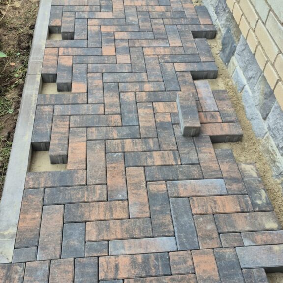 Mixed colour rectangular paving blocks beside a wall
