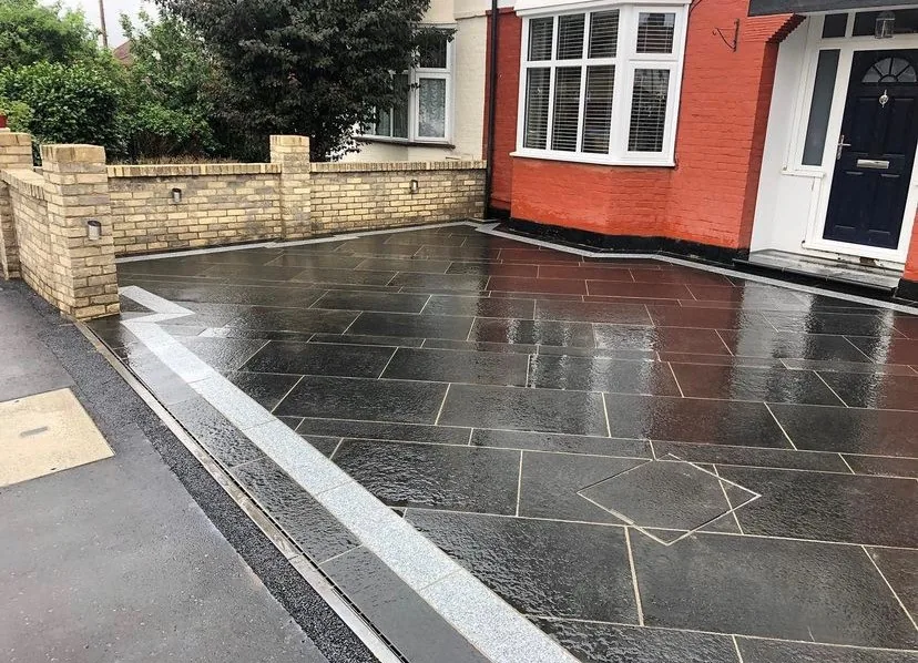 Dark slate paving outside a red brick house